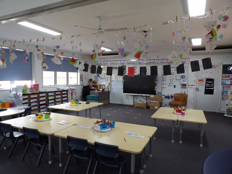A classroom with colourful banners hanging on the ceiling and student artwork on display.